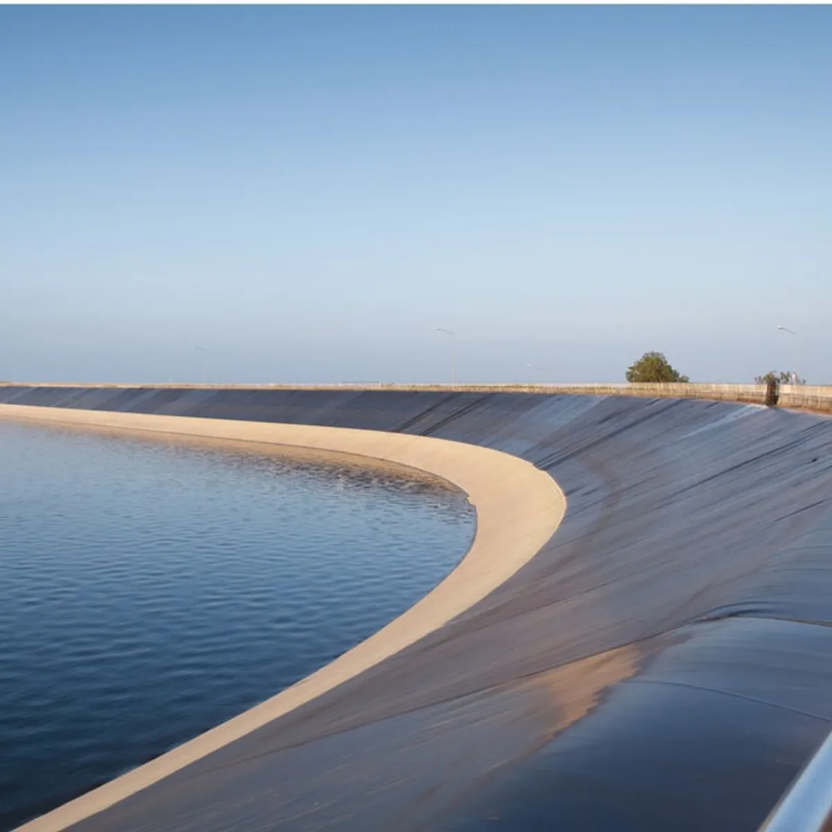 HDPE geomembrane lining a large open water reservoir holding stored water on the slope